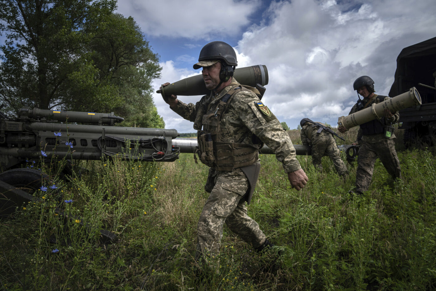 Ukraiński żołnierz niesie 155 mm pocisk artyleryjski przed ostrzelaniem rosyjskich pozycji z dostarczonej przez USA haubicy M777 w obwodzie charkowskim na Ukrainie, foto: AP Photo/Evgeniy Maloletka