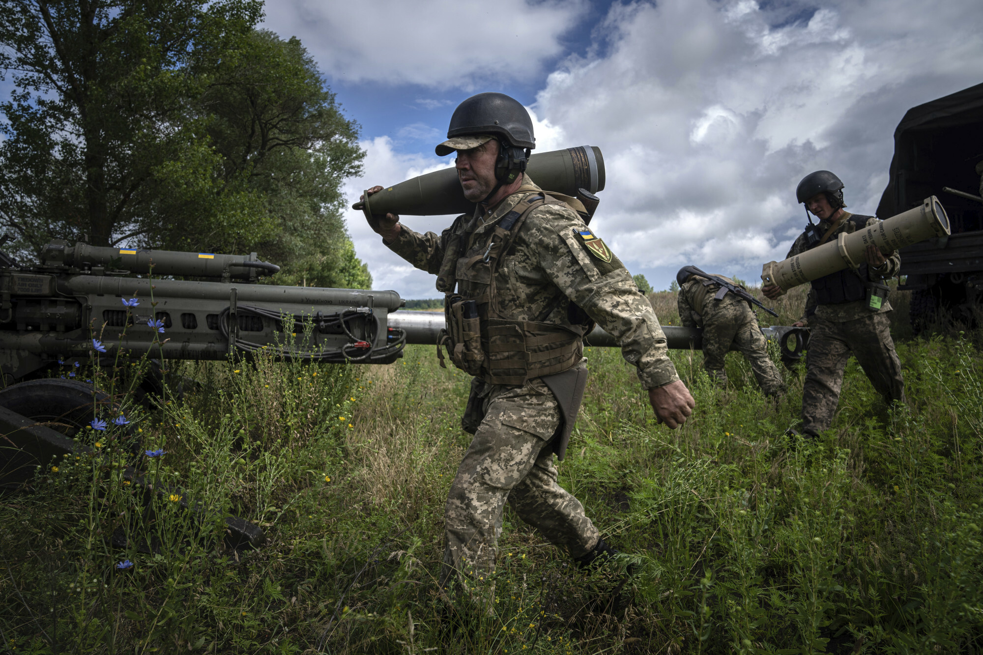 Ukraiński żołnierz niesie 155 mm pocisk artyleryjski przed ostrzelaniem rosyjskich pozycji z dostarczonej przez USA haubicy M777 w obwodzie charkowskim na Ukrainie, foto: AP Photo/Evgeniy Maloletka